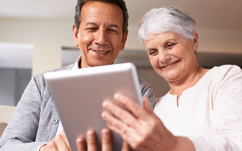 Senior couple smiling and looking at a tablet