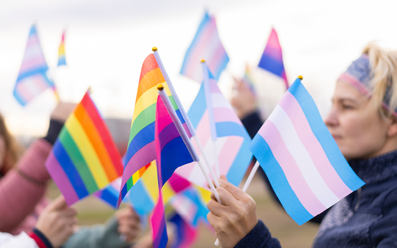 A woman waving pride flags at an event.