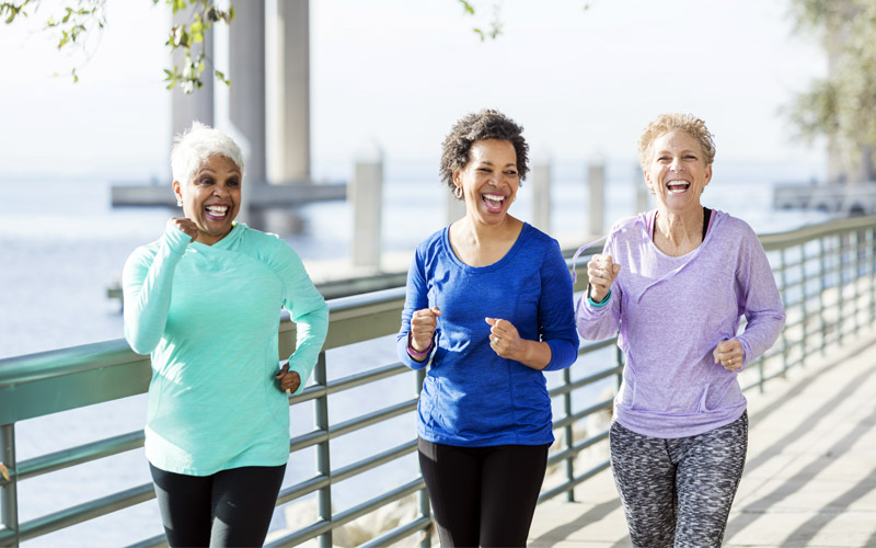 Three women in retirement jogging on a boardwalk